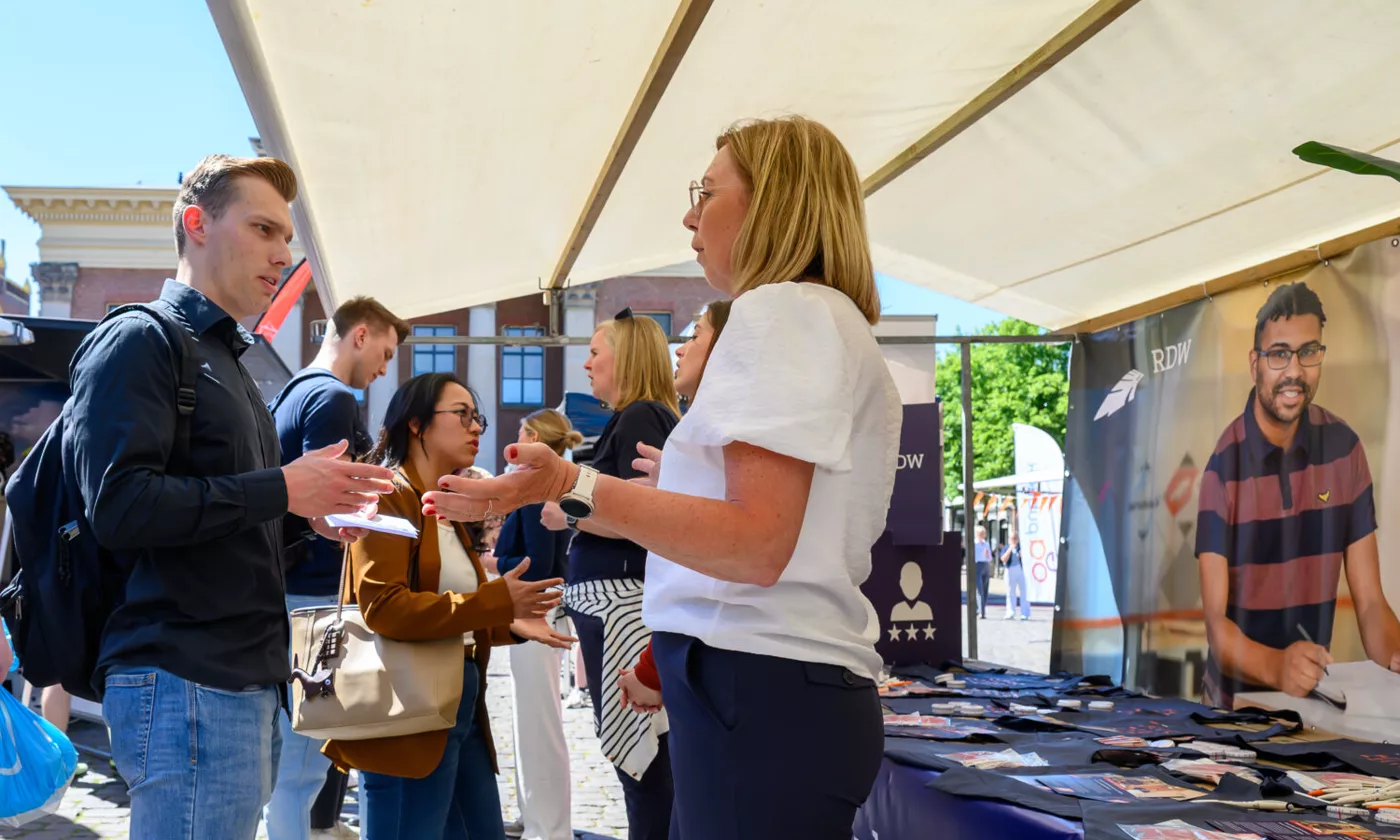 Bezoekers in gesprek met werkgevers op de Banenmarkt in Emmen